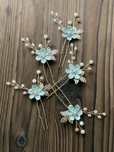 Detailed close-up of 5-piece floral hair pins with mint flowers, pearls, and gold leaves