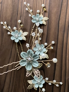 Detailed macro view of 5-piece floral bridal hair pins with green petals and pearls