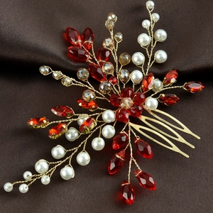 Close-up of emerald style red crystal and pearl bridal hair comb on dark silk fabric