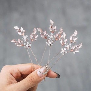Detailed close-up of set of three rose gold rhinestone leaf hair pins with pearls