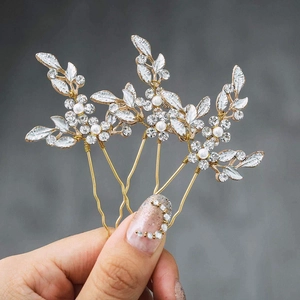 Detail of three U-shaped bridal hair pins with rhinestone leaves and white pearls