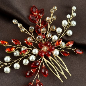 Macro detail of bridal hair comb with red crystals, white pearls, and gold wire