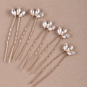 Detailed view of five U-shaped gold hair pins with sparkling marquise rhinestones