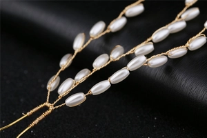 Dettaglio delle forcine dorate con eleganti perle bianche ovali e design a spiga di grano