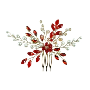 Macro detail of bridal hair comb with red emerald crystals and white pearls