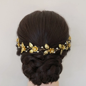Golden bridal headband with hollow flower leaf design and pearls on a hair model