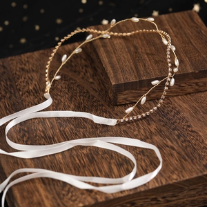 Elegant bridal headpiece with gold wire, pearls and crystals on dark wood background