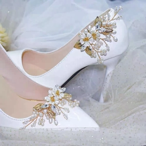 Détail d'un clip à chaussure mariée avec fleur blanche, perles et cristaux sur escarpin
