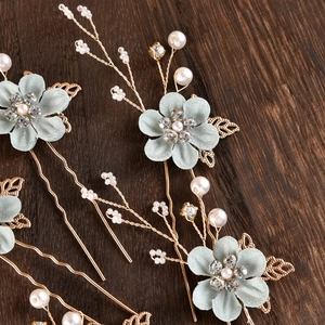 Detailed macro view of mint green fabric flower hair pins with pearls and crystals
