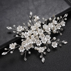 Detail of white resin flowers and crystals on a bridal hair clip with silver wire