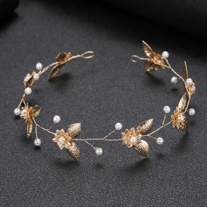 Golden bridal headband with hollow flowers, leaves and pearls on black background
