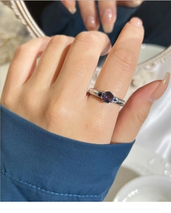 Detail shot of a ribbed silver ring with a round purple zircon and side stone accents