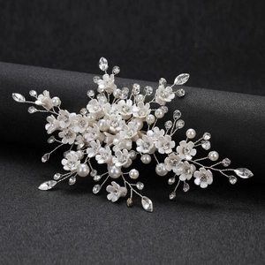 Elegant white floral bridal hair clip with sparkling rhinestones and pearls on a silver frame