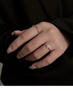 Detail of silver heart ring and cross band with zircon stones worn on hand