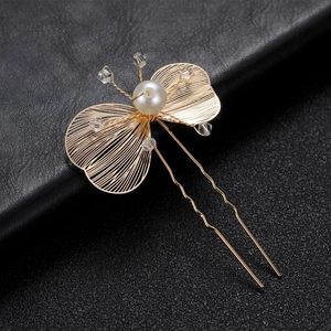 Macro detail of golden butterfly hair pin with wire-woven wings and pearls decoration