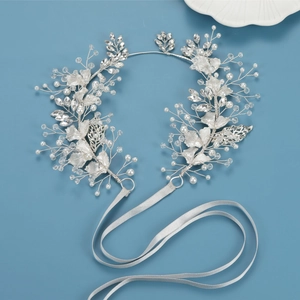 Close-up of bridal leaf hairband with rhinestones, pearls and white ribbons
