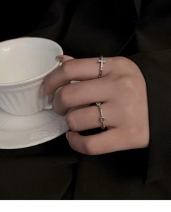 Detail of silver cross ring with cubic zirconia and matching minimalist wavy band