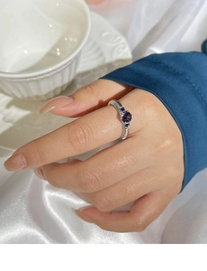 Close-up of vintage silver ring with purple zircon and blue side stones on model's finger