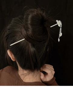 Détail de l'épingle à cheveux fleurie en argent avec pompons portée sur un chignon