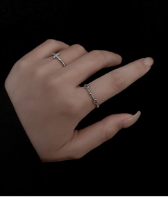 Detailed close-up of a silver-colored cross ring with pavé crystals for daily layering