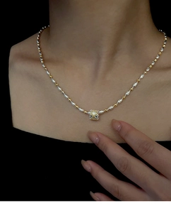 Vista dettagliata del ciondolo bicolore oro e argento su una catena a clavicola sottile