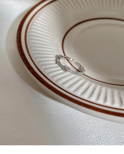 Detail of silver heart ring with white zircons on a vintage ceramic plate display