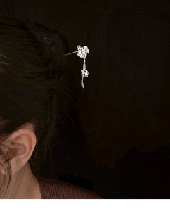 Détail d'une épingle à cheveux fleurie argentée avec pompons sur un chignon élégant