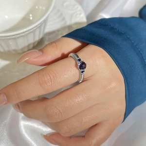Vintage silver ring with purple zircon and blue side stones on white silk background