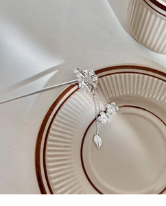 Détail d'une épingle à cheveux fleurie argentée avec pompons sur céramique