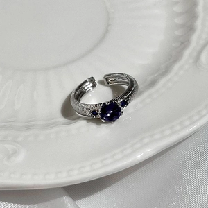 Silver open ring with purple zircon stone and textured band on white porcelain