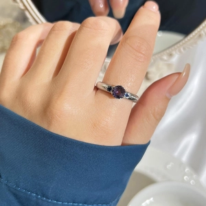 Elegant silver ring with round purple zircon and blue side stones on model's finger