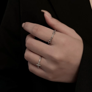 Minimalist silver rings with cross and rope design shown on model hand
