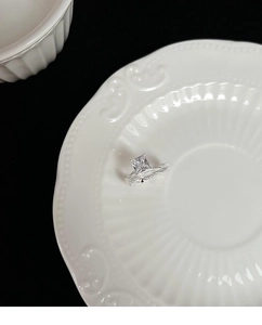 Λεπτομέρεια macro δαχτυλιδιού με ζιργκόν princess cut και πλεκτή ταινία σε κεραμικό δίσκο