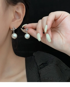 Close-up of elegant silver knotted pearl earrings on model with high gloss finish