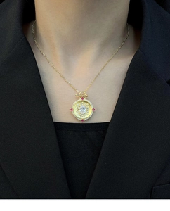 Detail of vintage gold flower pendant necklace with white stone and red accents on model