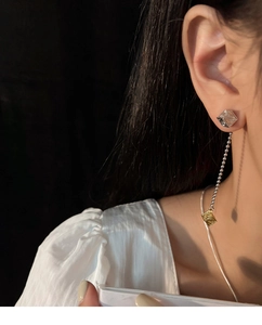 Detail of asymmetric tassel earrings featuring vintage engraved cubes and bead chains