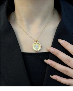 Detail of vintage sunburst round pendant with red gems on elegant gold necklace