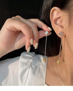 Detail of silver needle tassel earrings featuring two-tone cubes with vintage patterns