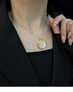 Macro shot of vintage gold medal pendant necklace featuring colorful gemstones on a model