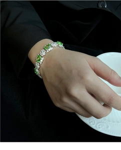 Détail du bracelet en zircon vert pomme au poignet avec une tenue professionnelle chic