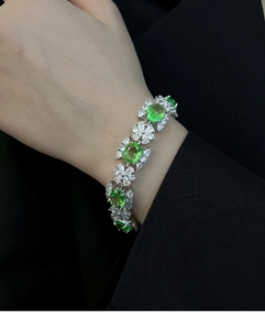 Gros plan d'un bracelet fleur en zircon vert sur poignet avec monture en argent poli