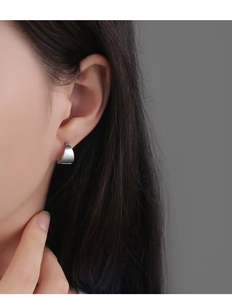 Boucle d'oreille géométrique en C argent poli montrant un design minimaliste sur le mannequin