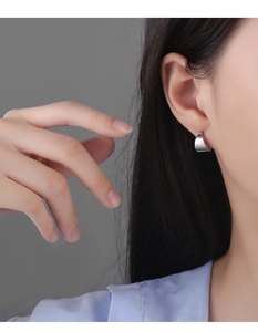 Gros plan de boucles d'oreilles incurvées en argent poli portées par un mannequin