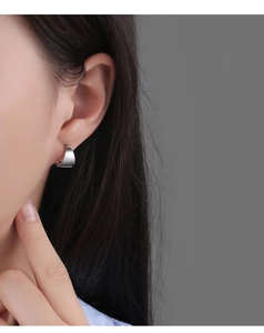 Gros plan de la boucle d'oreille créole minimaliste en argent portée par un modèle