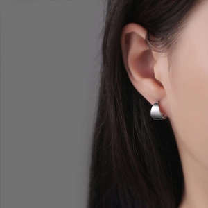 Boucles d'oreilles créoles courbées minimalistes en argent poli portées par modèle