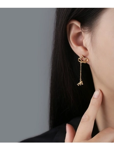 Close-up of gold star earrings with cubic zirconia and bear charms on a model