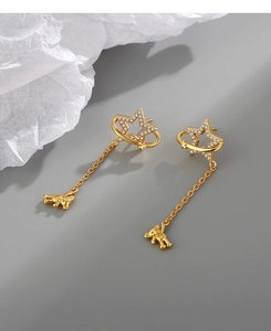 Close-up of golden star drop earring with sparkling rhinestones and a bear charm