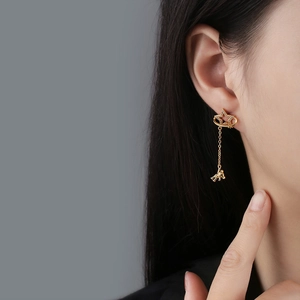 Gold star and bear tassel earrings with sparkling crystals worn by a model