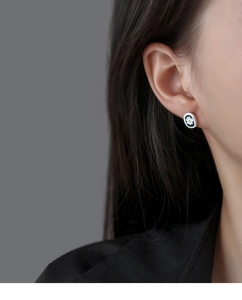 Close-up of elegant daisy flower stud earrings with enamel details on earlobe