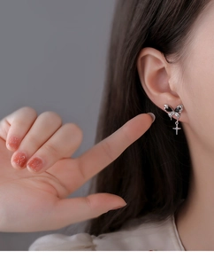 Detail of silver bow earrings with black zircon and hanging star pendant on ear